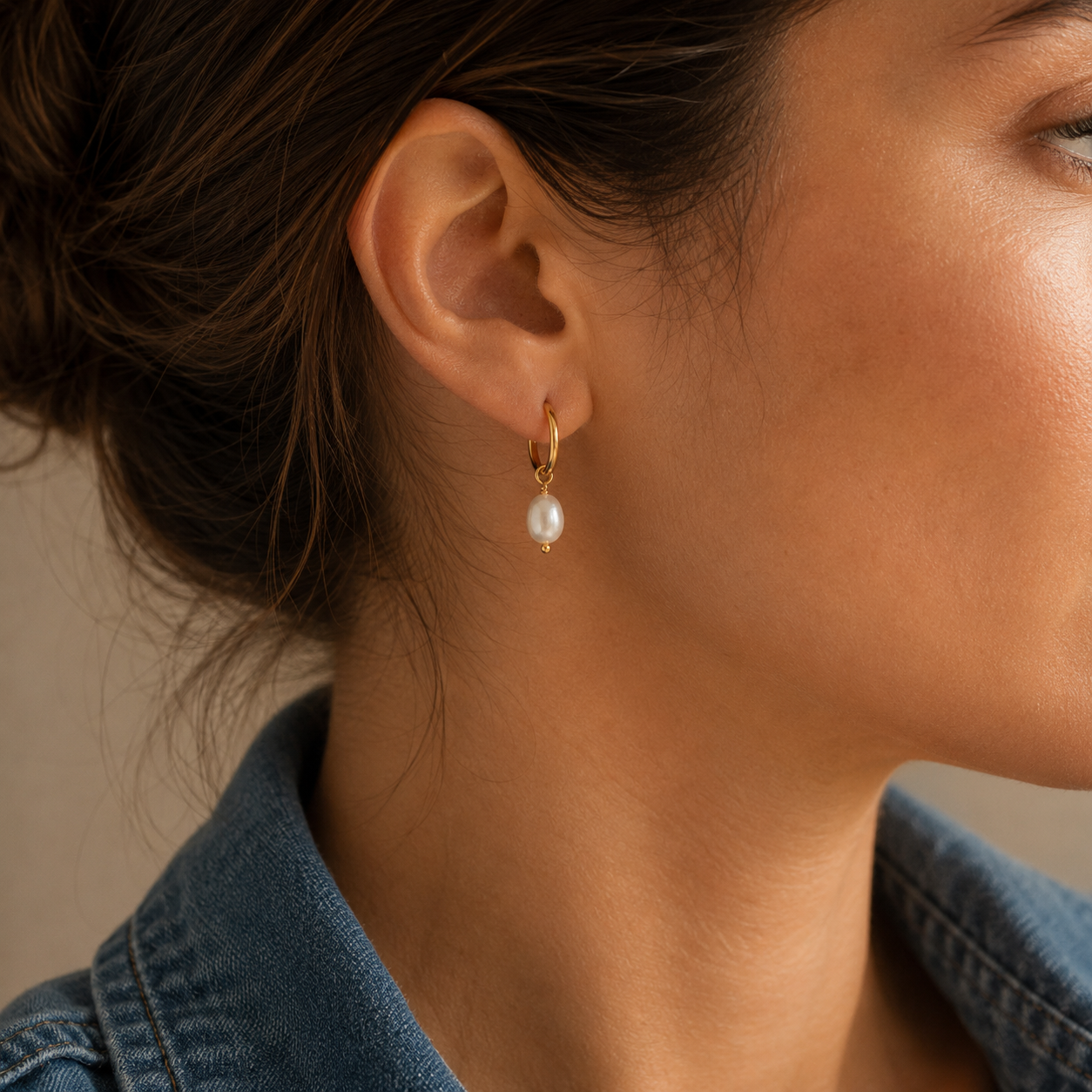 Close-up of gold freshwater pearl drop hoop earring