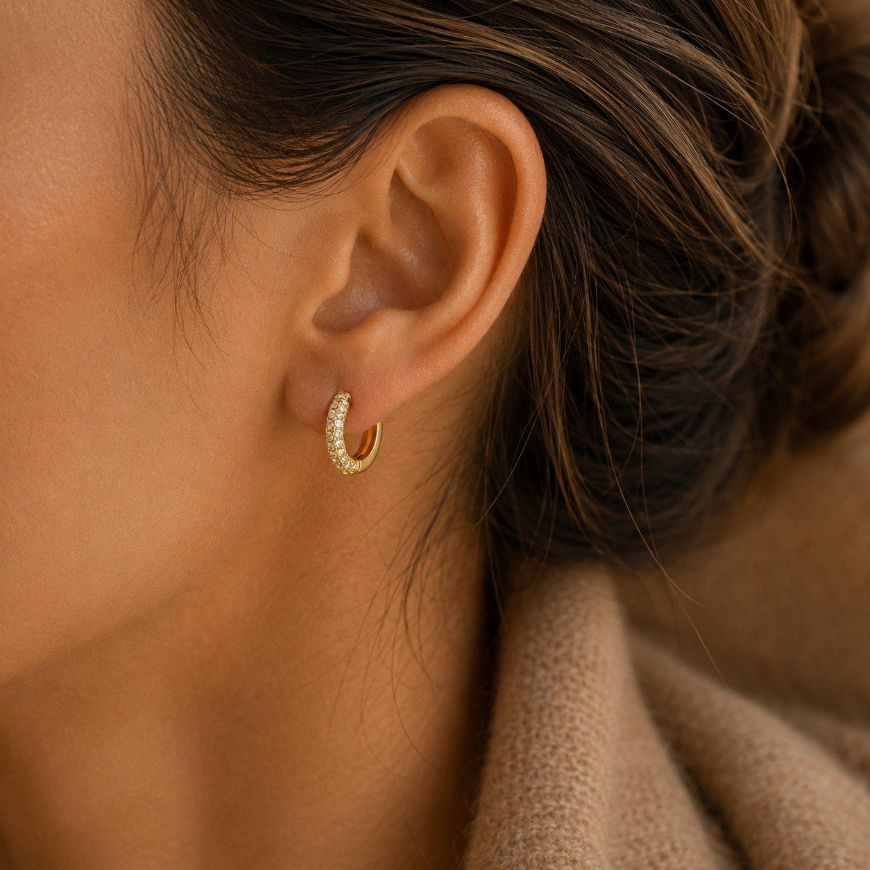 Close-up of gold pavé huggie hoop earring on model