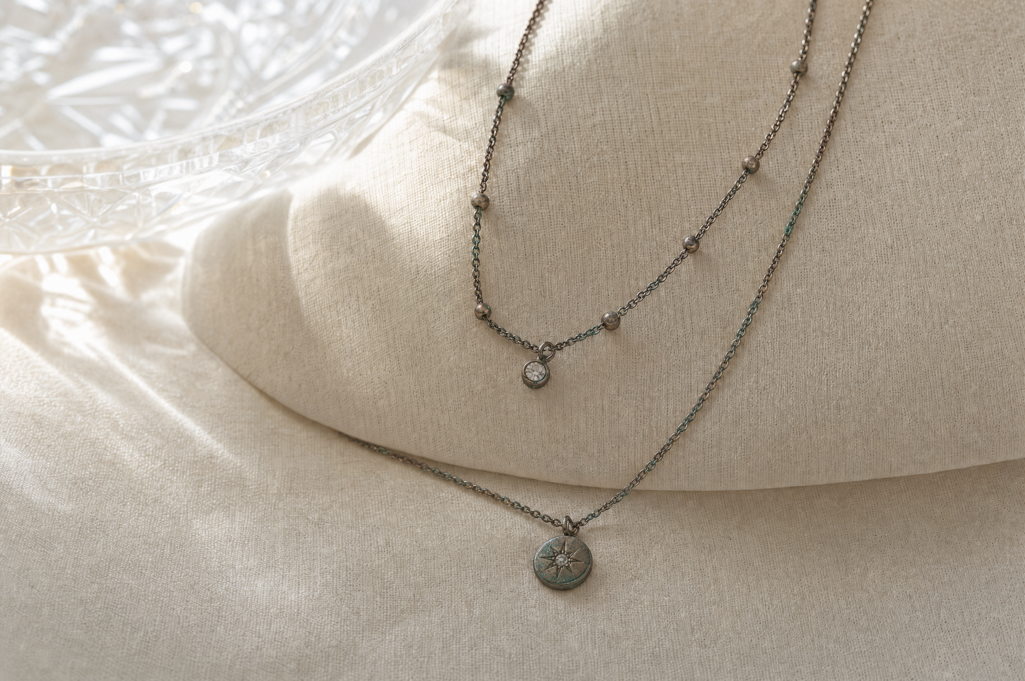Tarnished dull necklace on ivory linen - ordinary plating after months of wear