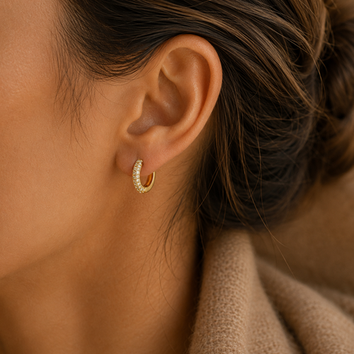 Close-up of gold pavé huggie hoop earring on model
